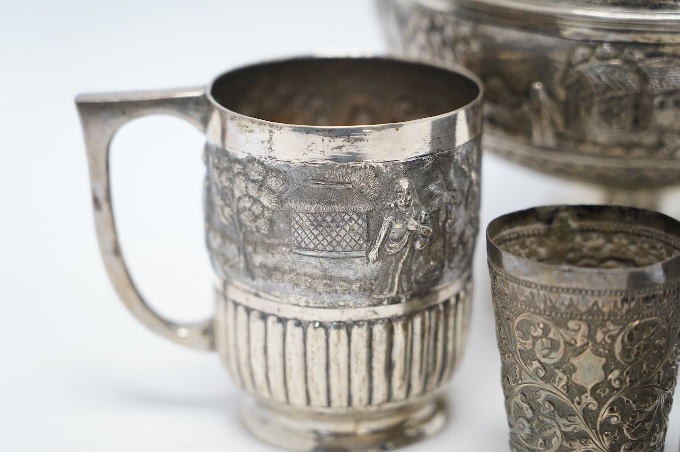 An Indian repousse white metal pedestal bowl, diameter 15.5cm (a.f.), a similar mug, small vase, condiment and small beaker. Condition - poor to fair